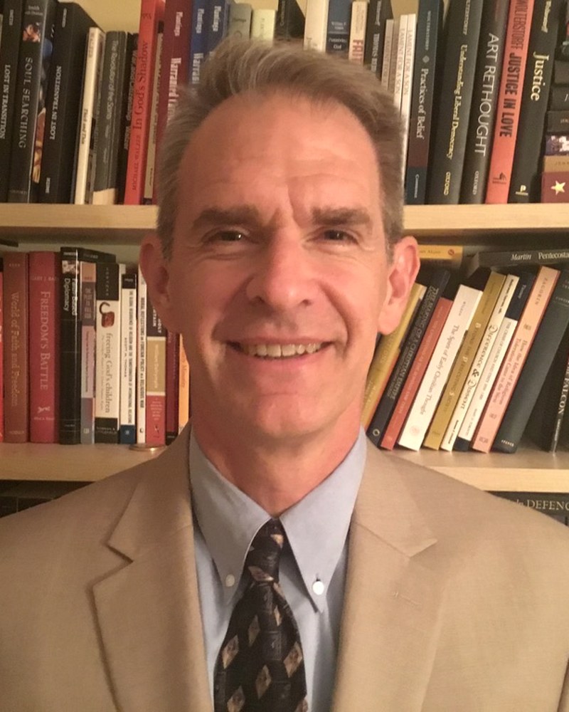 Christopher J. Eberle standing in front of bookshelves